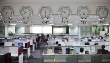 Workers are pictured beneath clocks displaying time zones in various parts of the world at an outsourcing centre in Bangalore